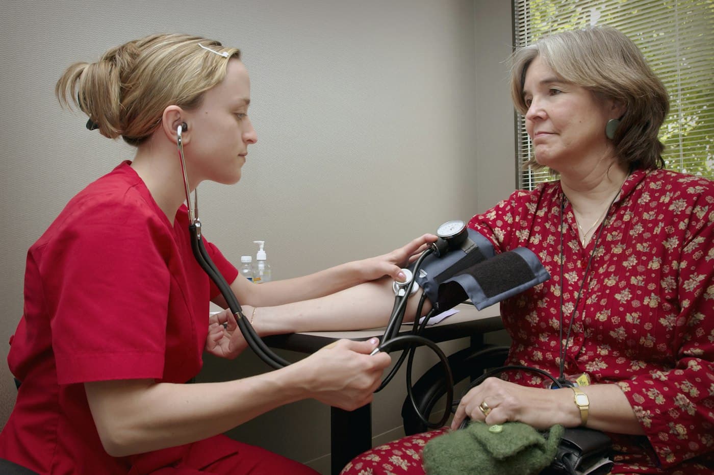 A nurse taking a patient's blood pressure with a cuff and stethoscope